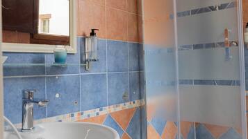 Une salle de bain avec un lavabo, un miroir et une douche.