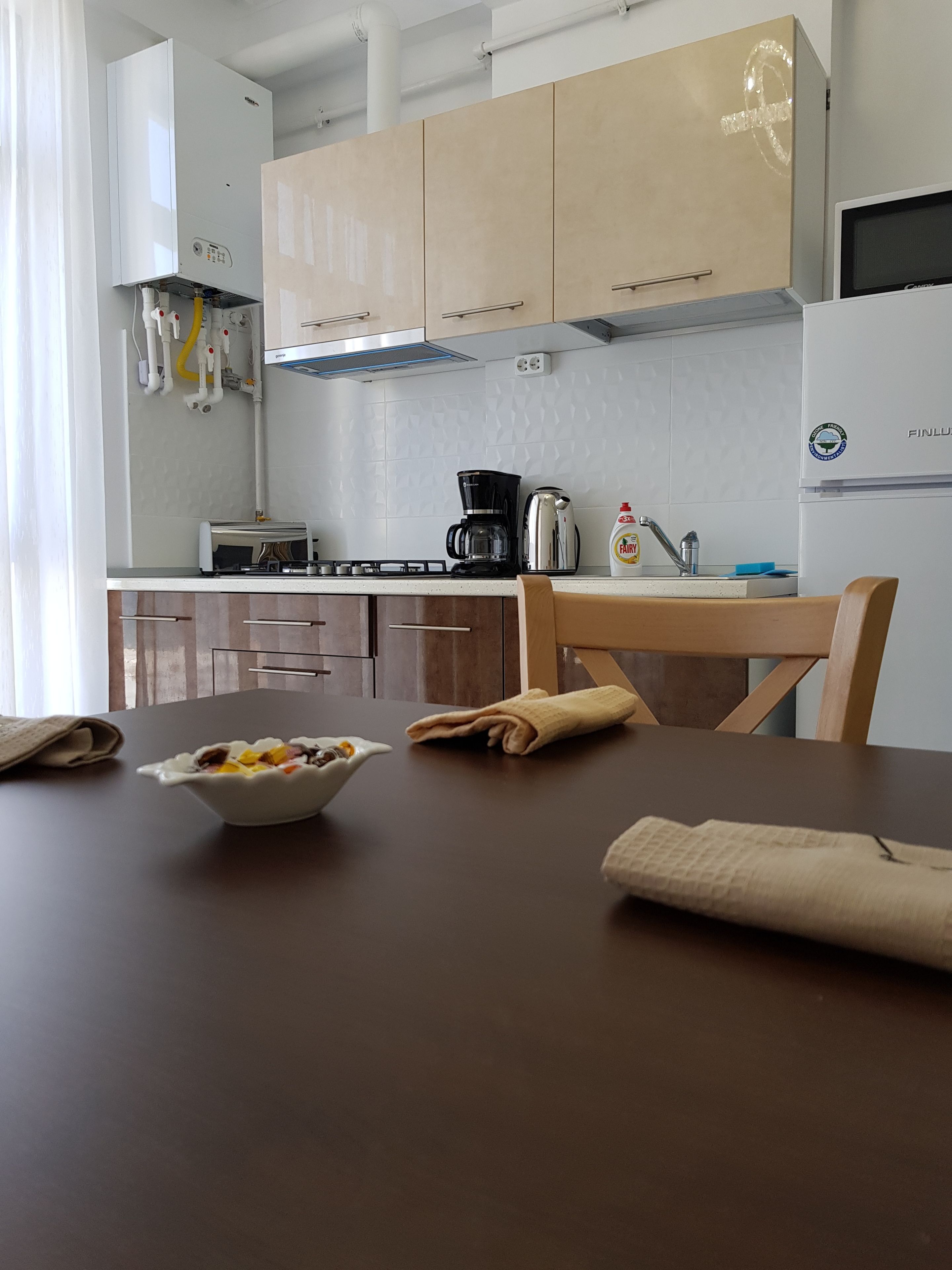 A modern kitchen with white cabinets, a stove, a coffee maker, and a sink.