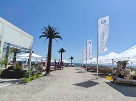Una playa cerca, arena blanca, sillas reclinables de playa, sombrillas
