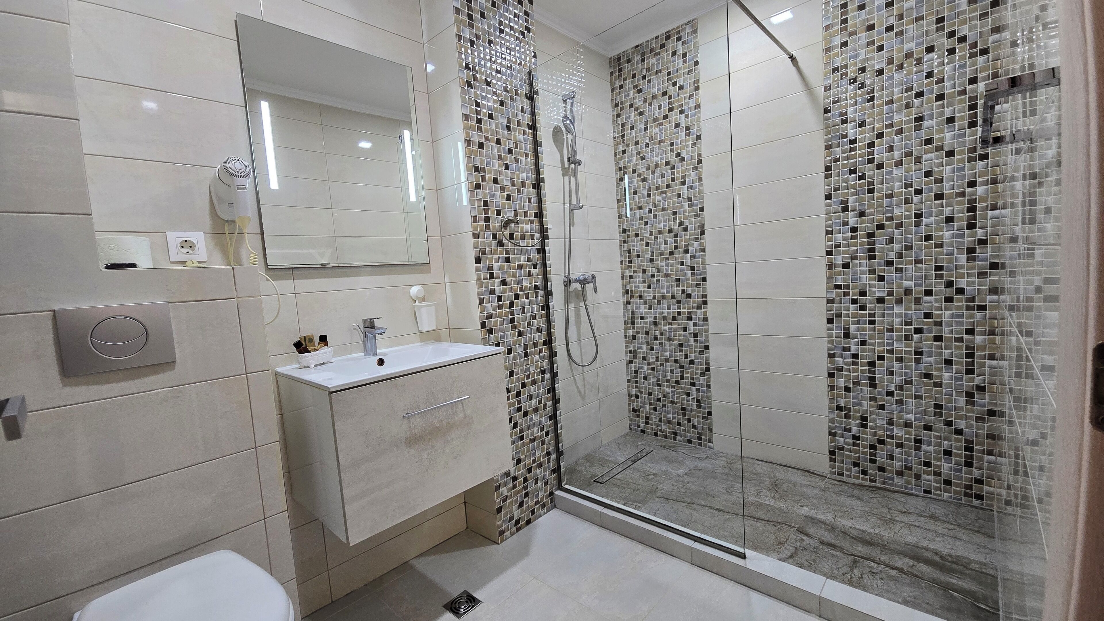 A modern bathroom with a glass-enclosed shower, a vanity with a sink, and a toilet.