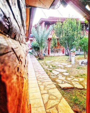 A stone pathway leading to a courtyard with a palm tree and potted plants. - Halise Apart (Datça)