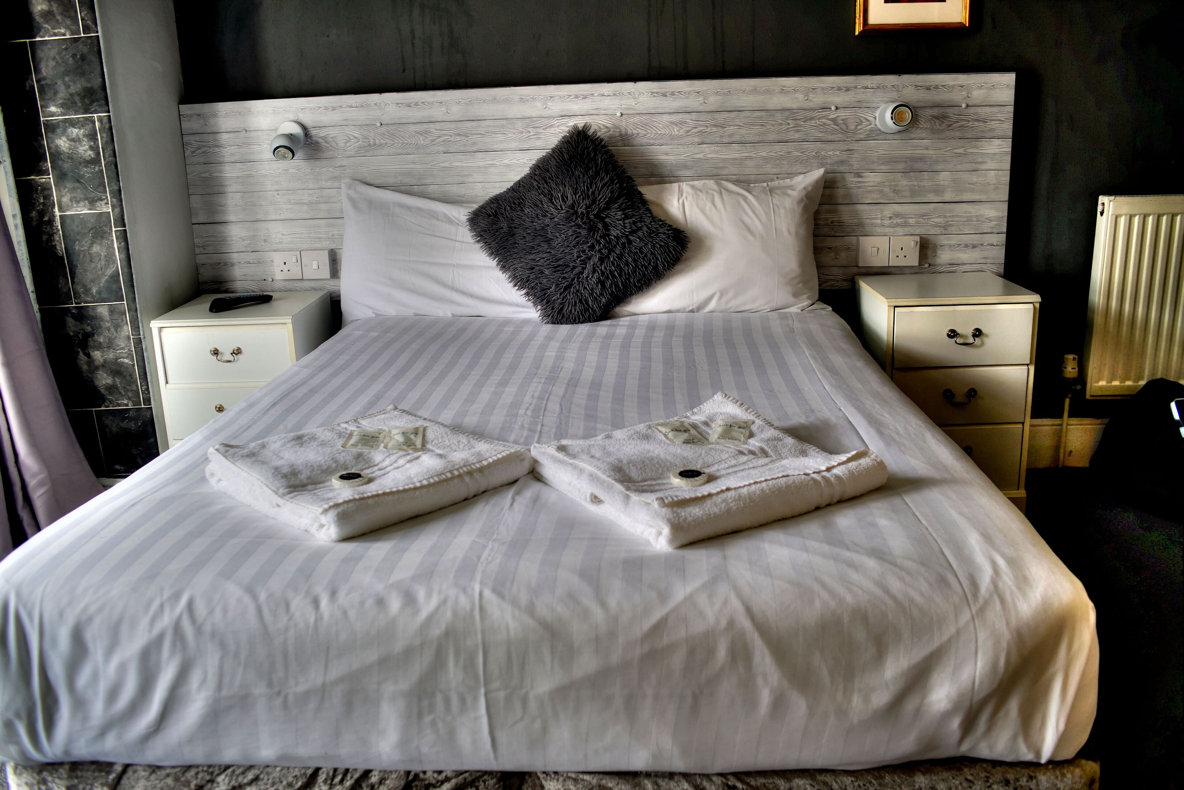 Un lit bien fait, avec deux serviettes, un oreiller moelleux et une table de chevet avec une lampe.