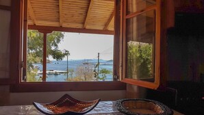 A room with a large window overlooking a body of water, a wooden ceiling, and two decorative bowls on the windowsill. - Shipwreck House (Zakynthos)