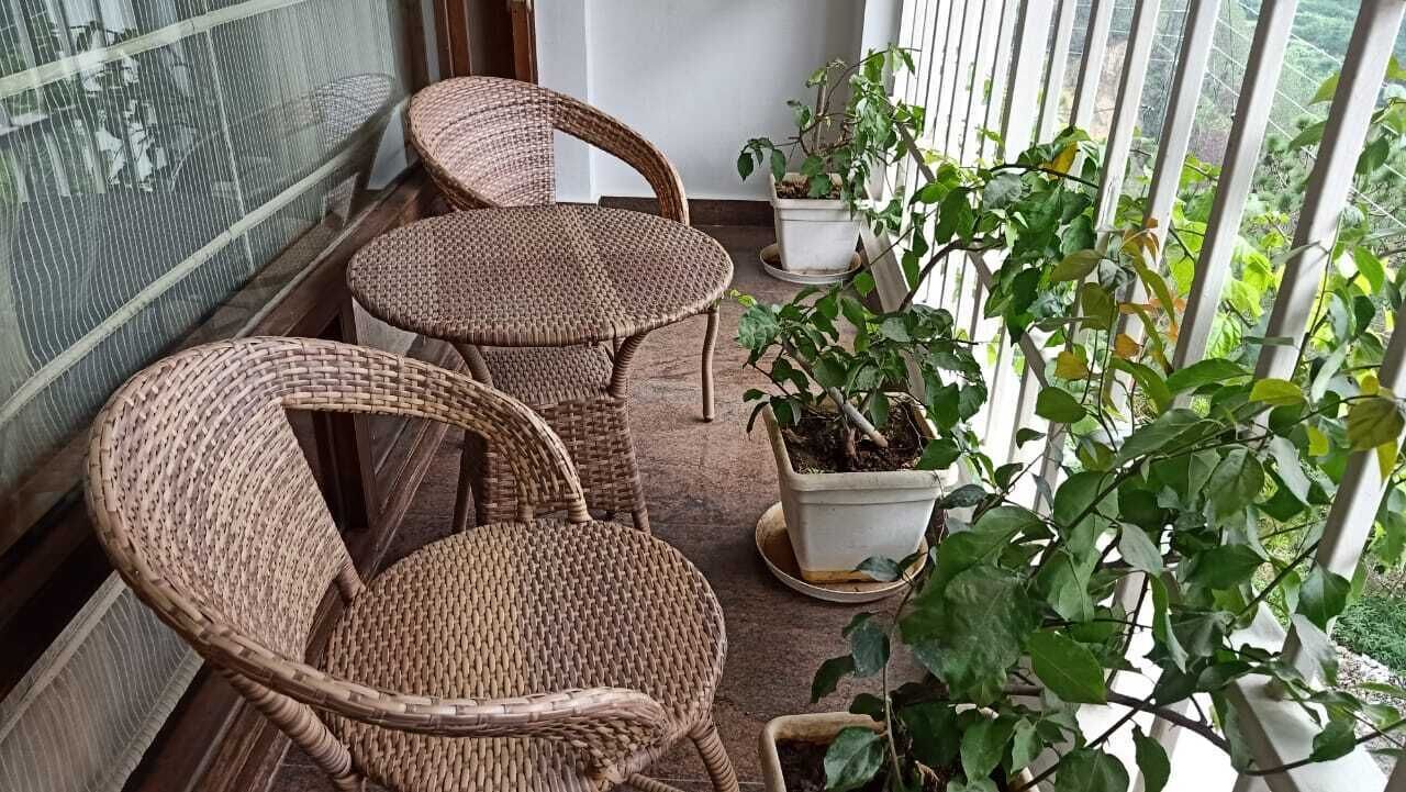 Un balcón con sillas de mimbre y plantas en macetas.