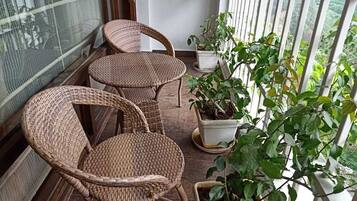 Un balcón con sillas de mimbre y plantas en macetas.