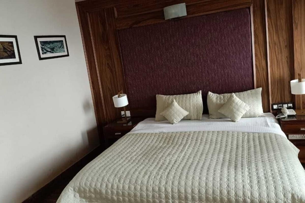 A neatly made bed with a white quilt, two bedside lamps, and a wooden headboard.
