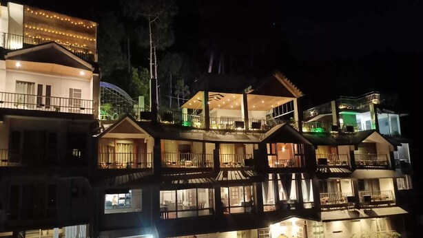 A multi-story hotel with balconies, large windows, and outdoor lighting. - Dunn Perk Manor (Solan)
