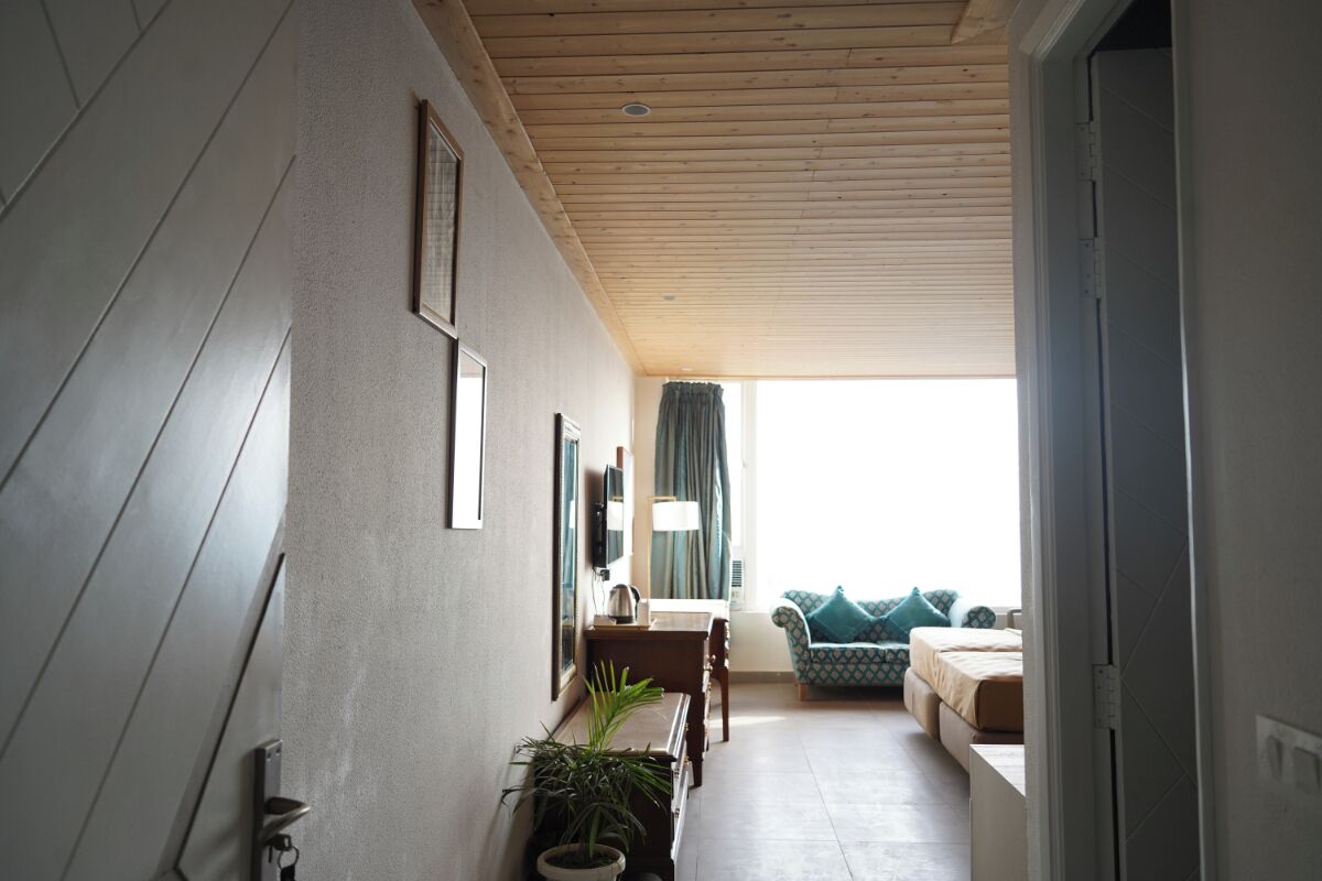 A corridor with a wooden ceiling, a sofa set, a table, and a potted plant.