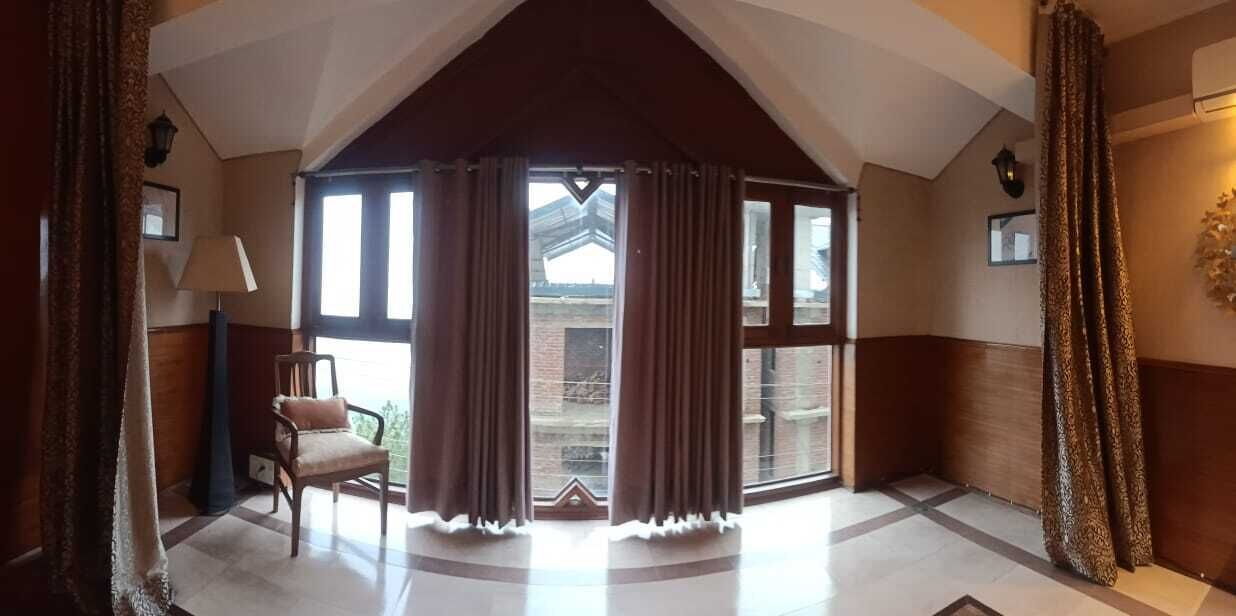 A room with a large bay window, a chair, and a lamp.