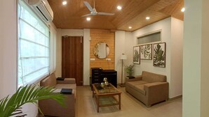 A living room with a ceiling fan, a sofa, a coffee table, and a mirror on the wall. - Dunn Perk Manor (Solan)