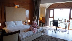 A bedroom with a large bed, a desk, and a view of the sea. - Dunn Perk Manor (Solan)