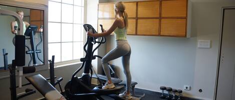 A gym with exercise equipment, a bench, and a window.