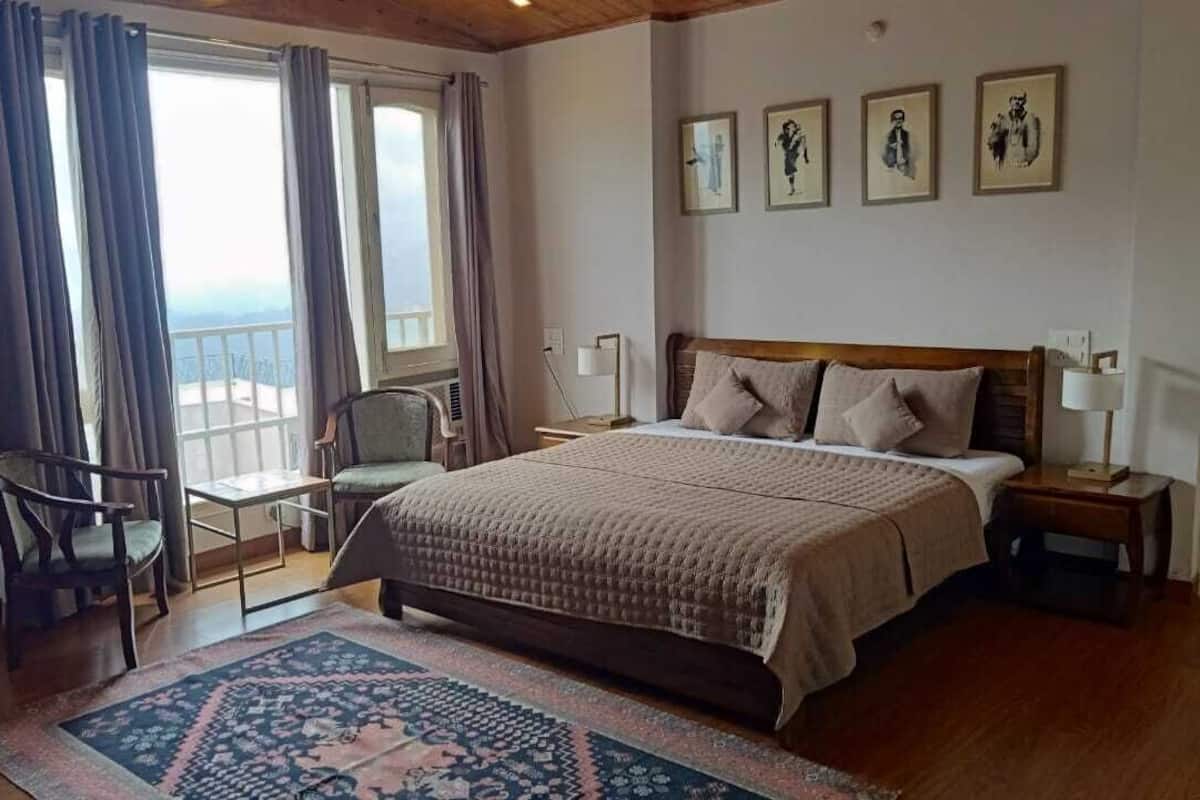 A bedroom with a large bed, a chair, a nightstand, and a window with curtains.
