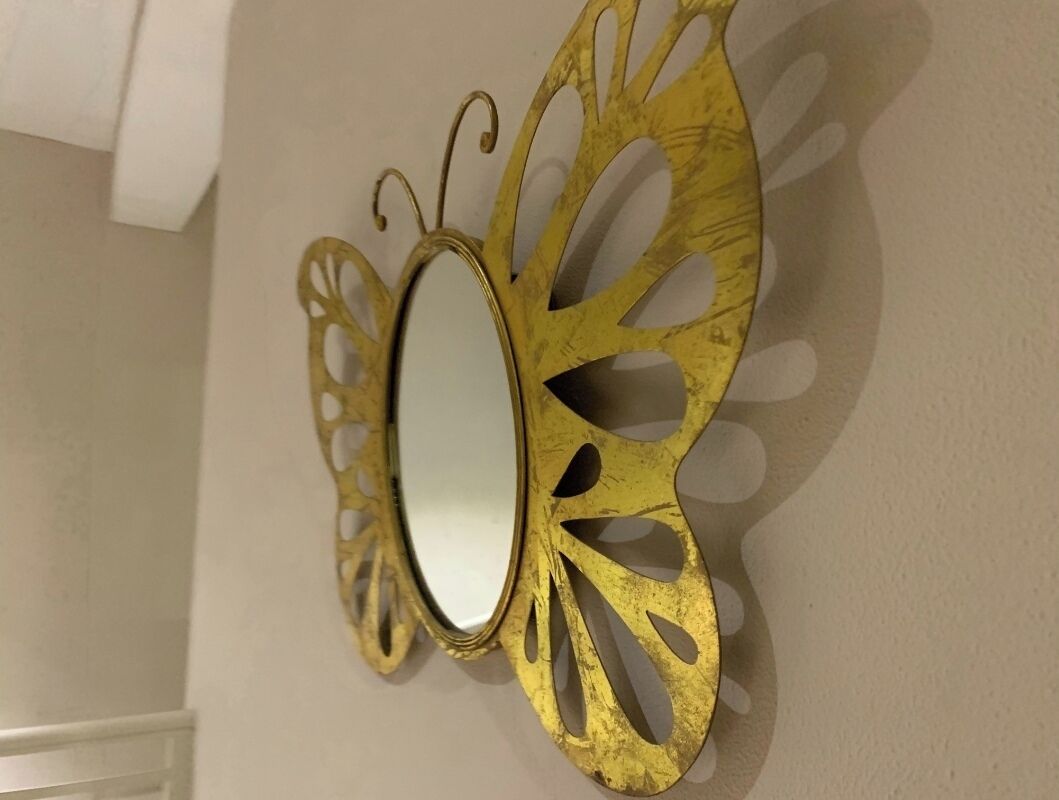 Espejo de pared con marco dorado y diseños calados.