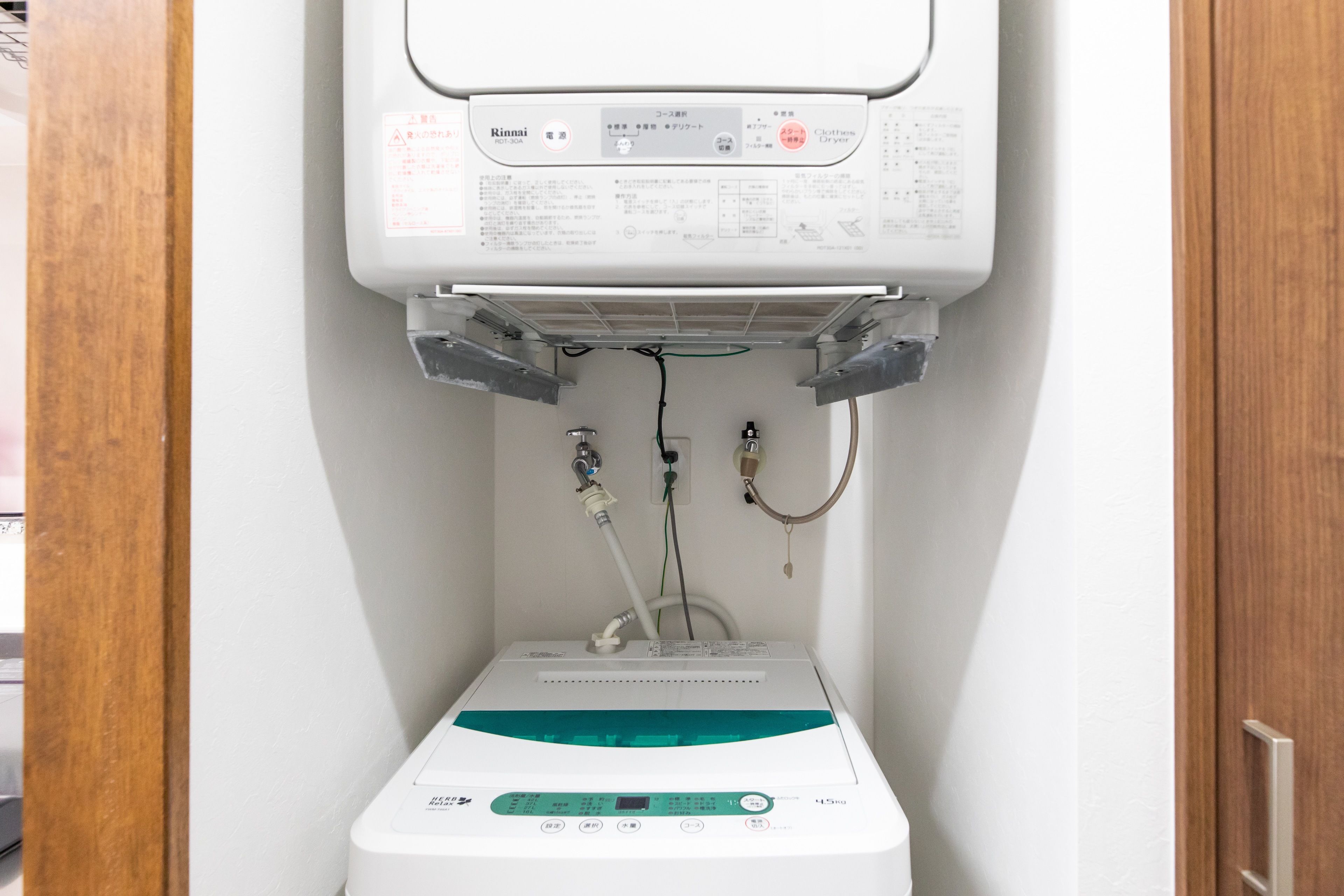 Calentador de agua con panel de control y tuberías, fijado en una pared blanca.