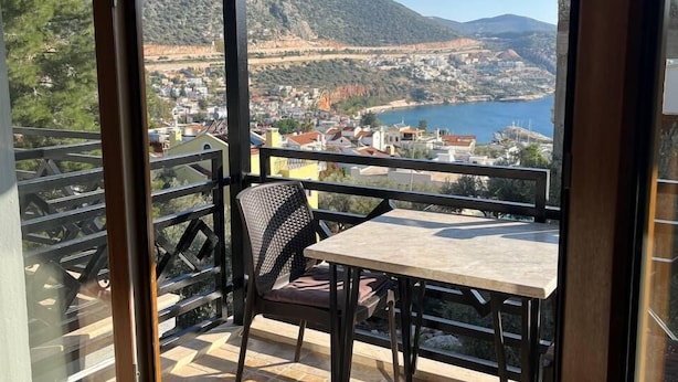 Un balcon avec une table et des chaises, offrant une vue sur une ville côtière et les montagnes.