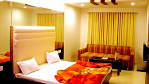 Una habitación de hotel con cama, sofá, una mesita y un ventilador de techo.