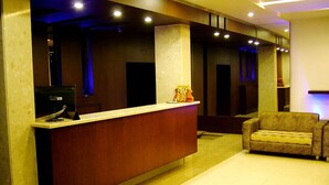 A reception area with a wooden reception desk, a computer, and a couch.
