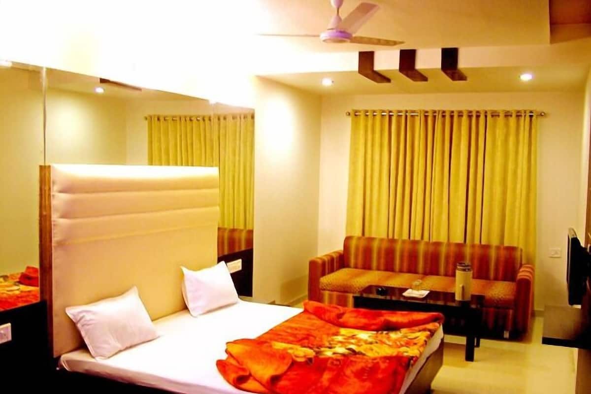 Een hotelkamer met een bed, een slaapbank, een bijzettafeltje en een plafondventilator.