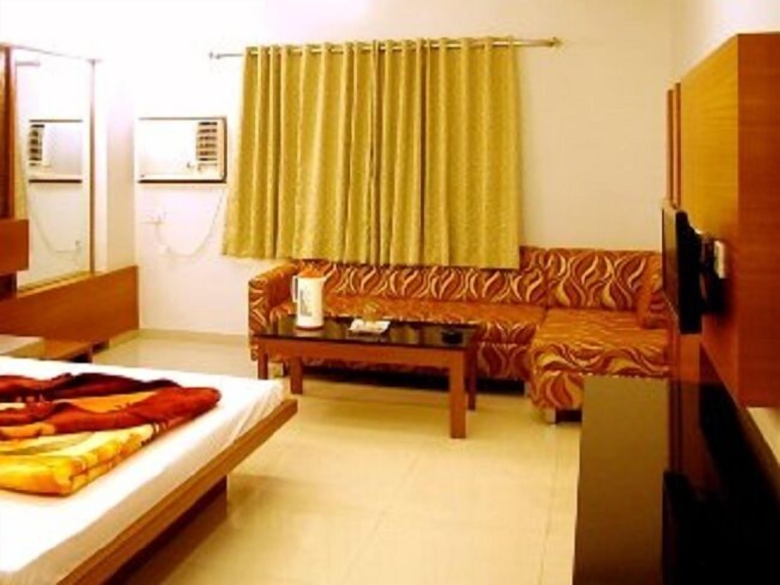 A hotel room with a bed, a sofa, a coffee table, and a television.
