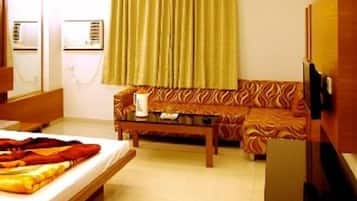 A hotel room with a bed, a sofa, a coffee table, and a television.