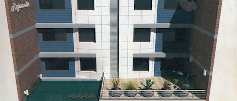 A hotel with a modern architectural design, featuring a central atrium with a staircase, multiple floors, and a rooftop garden with potted plants.