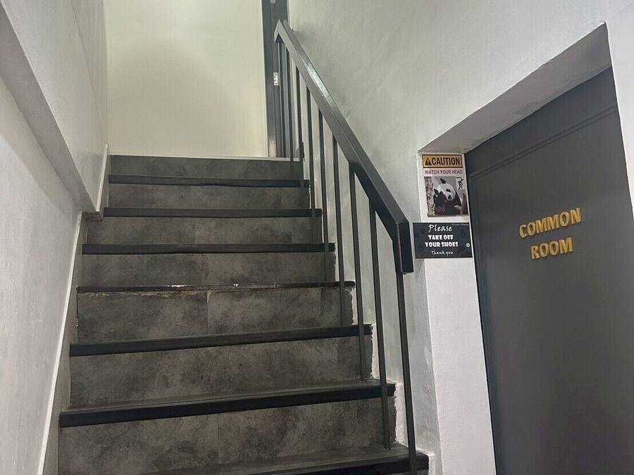 A staircase with a black railing, a red hanging decoration, and a sign indicating a common room.