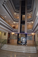 Un vestíbulo imponente con una escalera central, una recepción y un muro decorativo.