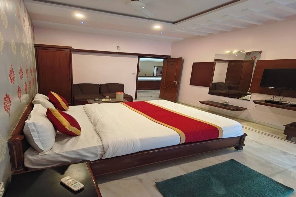 A bedroom with a large bed, bedside tables, a TV, a wardrobe, and a mirror.
