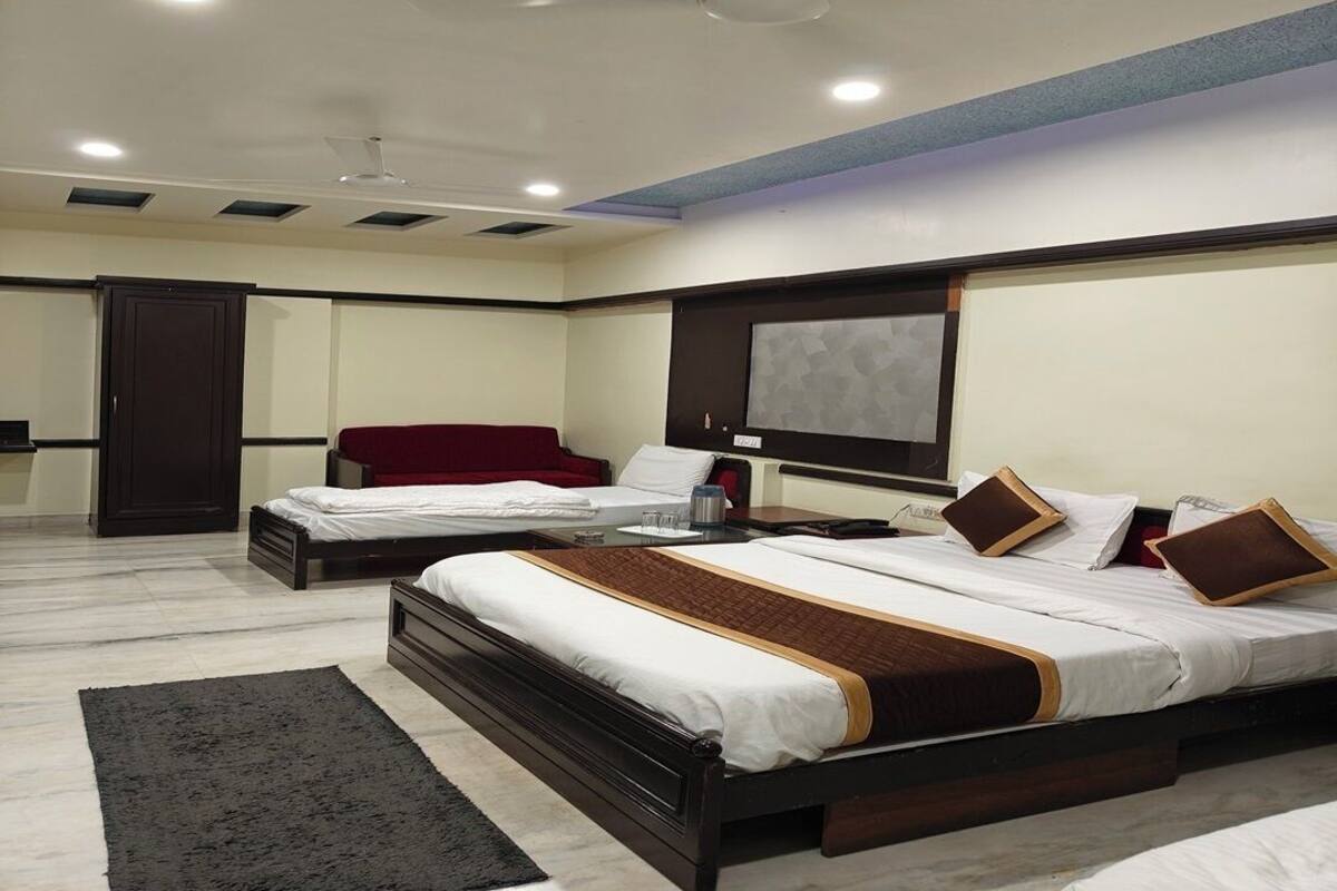A modern hotel room with two beds, a large TV, and a ceiling fan.