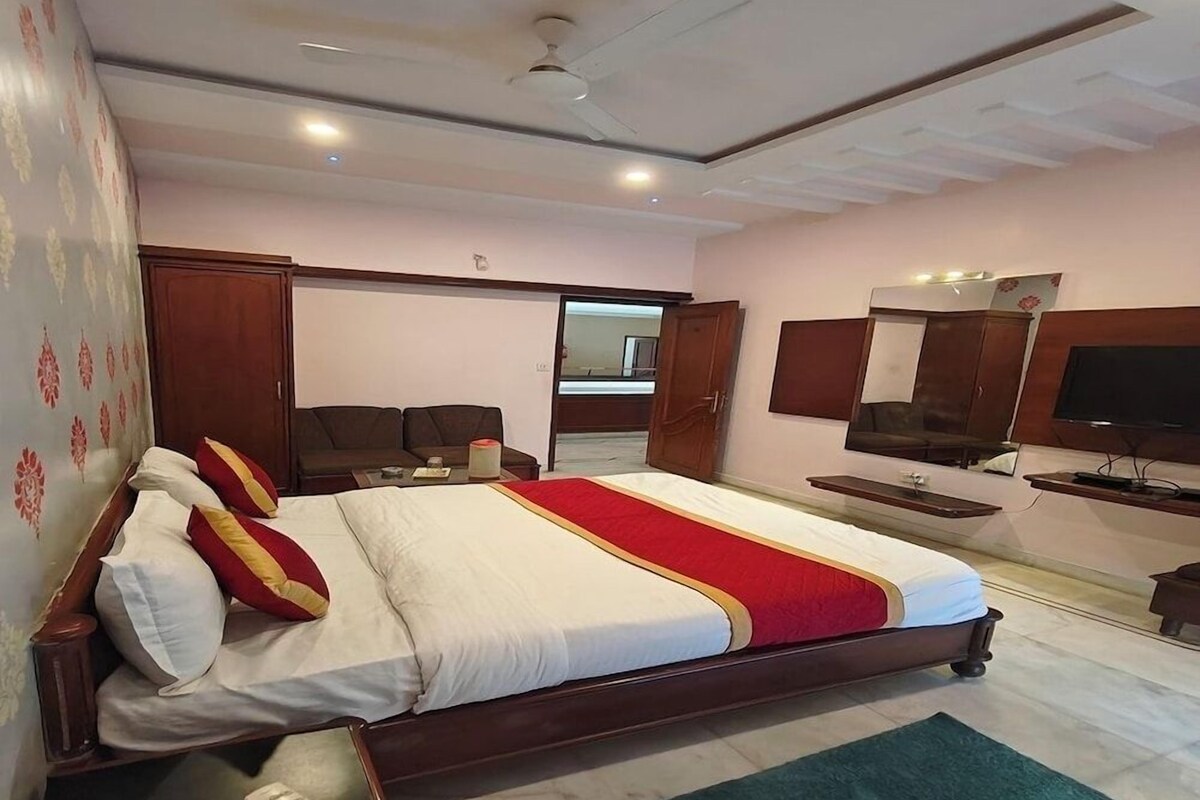 A hotel room with a large bed, a television, a wardrobe, and a bathroom visible through an open door.