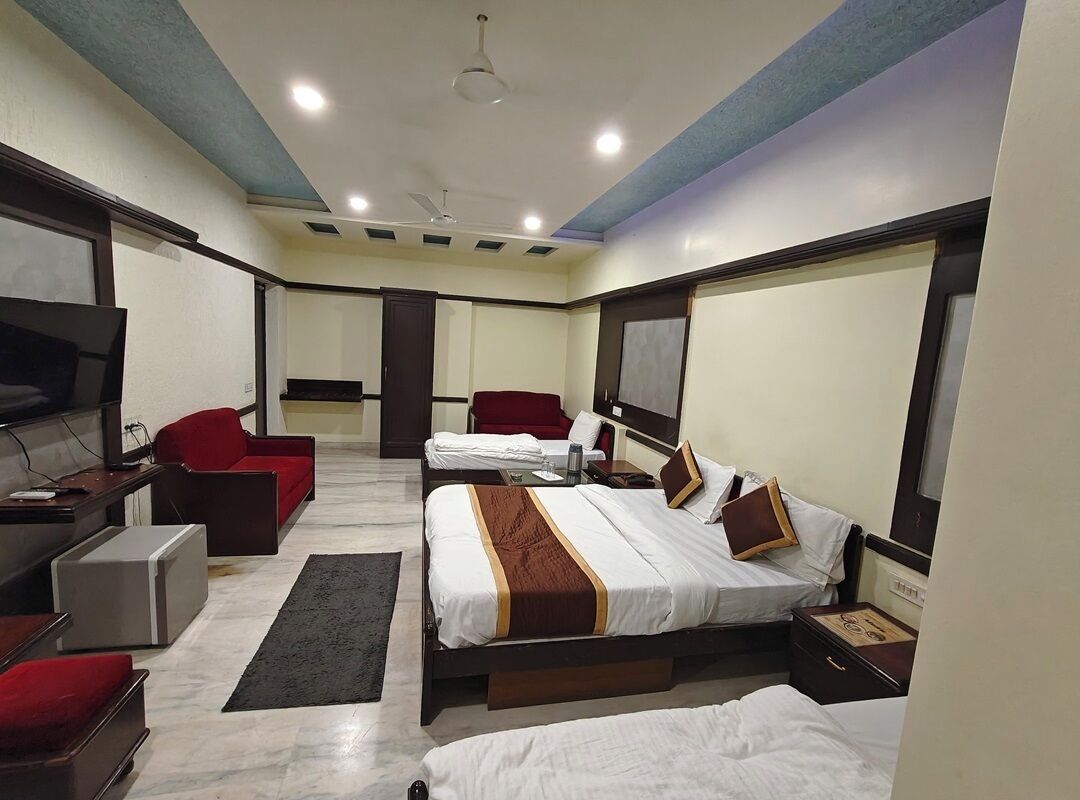 A hotel room with a bed, a desk, a chair, a TV, and a window.