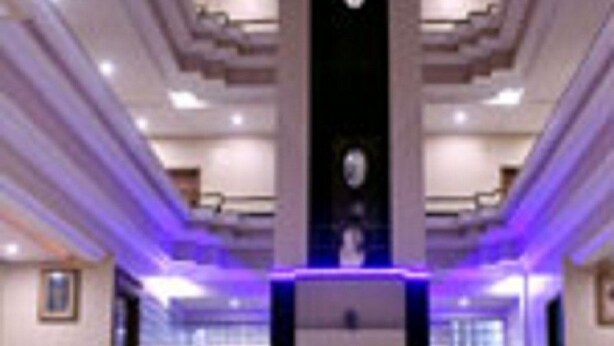 Un'ampia hall con una scalinata centrale, una reception e un moderno lampadario.