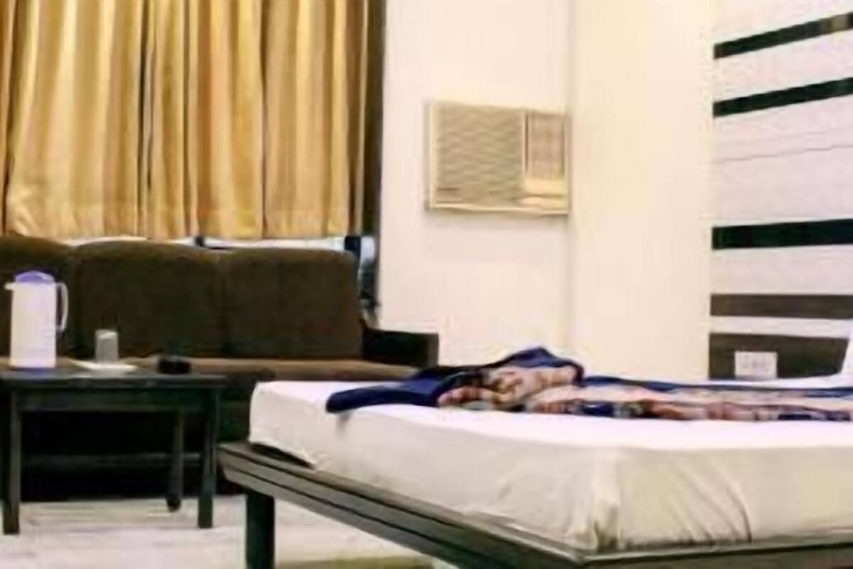 A hotel room with a bed, a sofa, a small table, and a window with curtains.