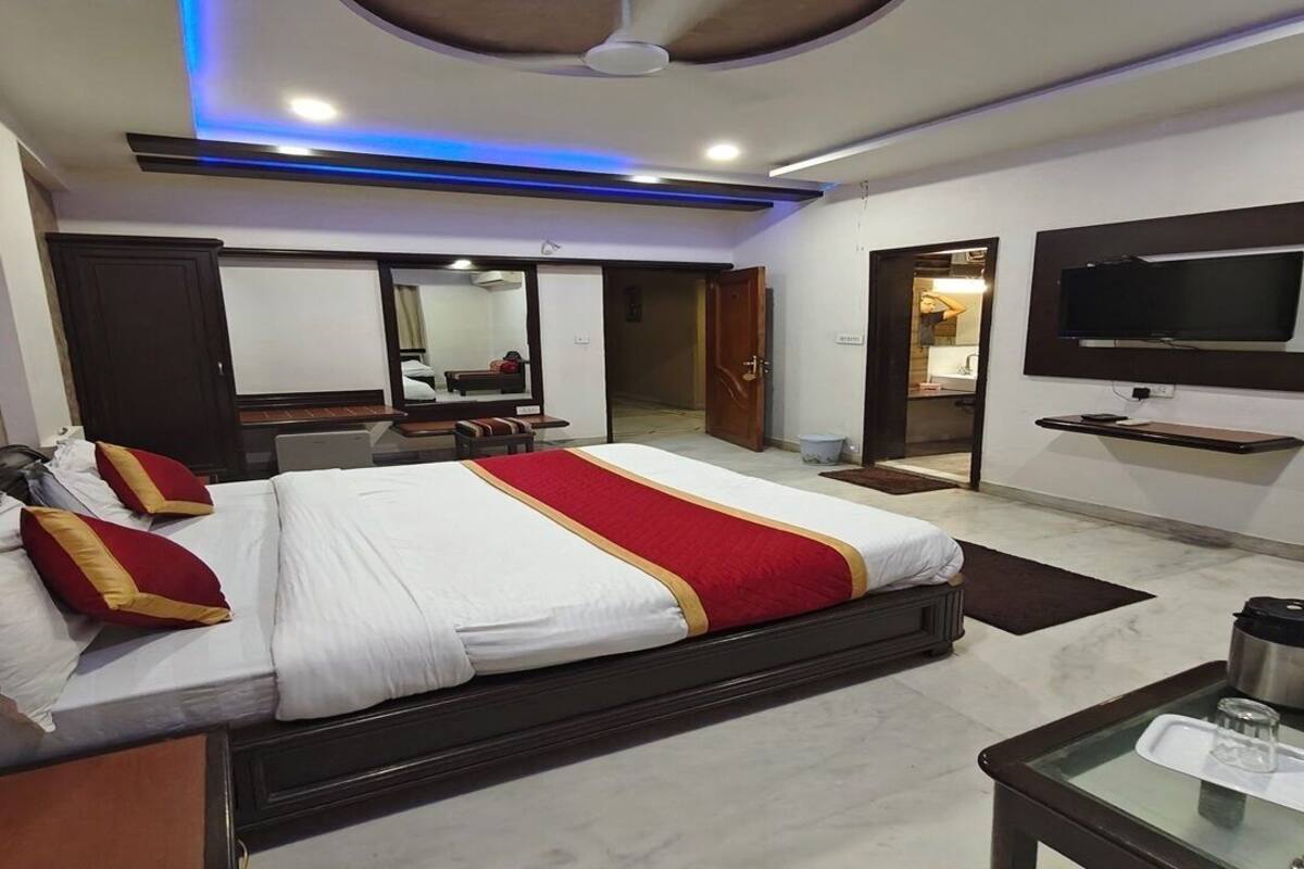 A hotel room with a bed, a TV, a desk, and a mirror.