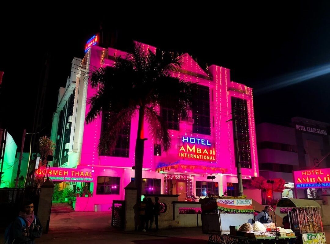 Un edificio bien iluminado con un letrero que dice 'Hotel Ambaji International'.
