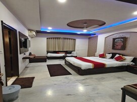 Un dormitorio de hotel moderno con una cama grande, una cama más pequeña, un escritorio y un ventilador de techo.