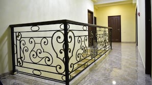 Corredor com piso de mármore e guarda-corpo de metal decorativo.