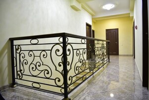 A hallway with a marble floor and a decorative metal railing.