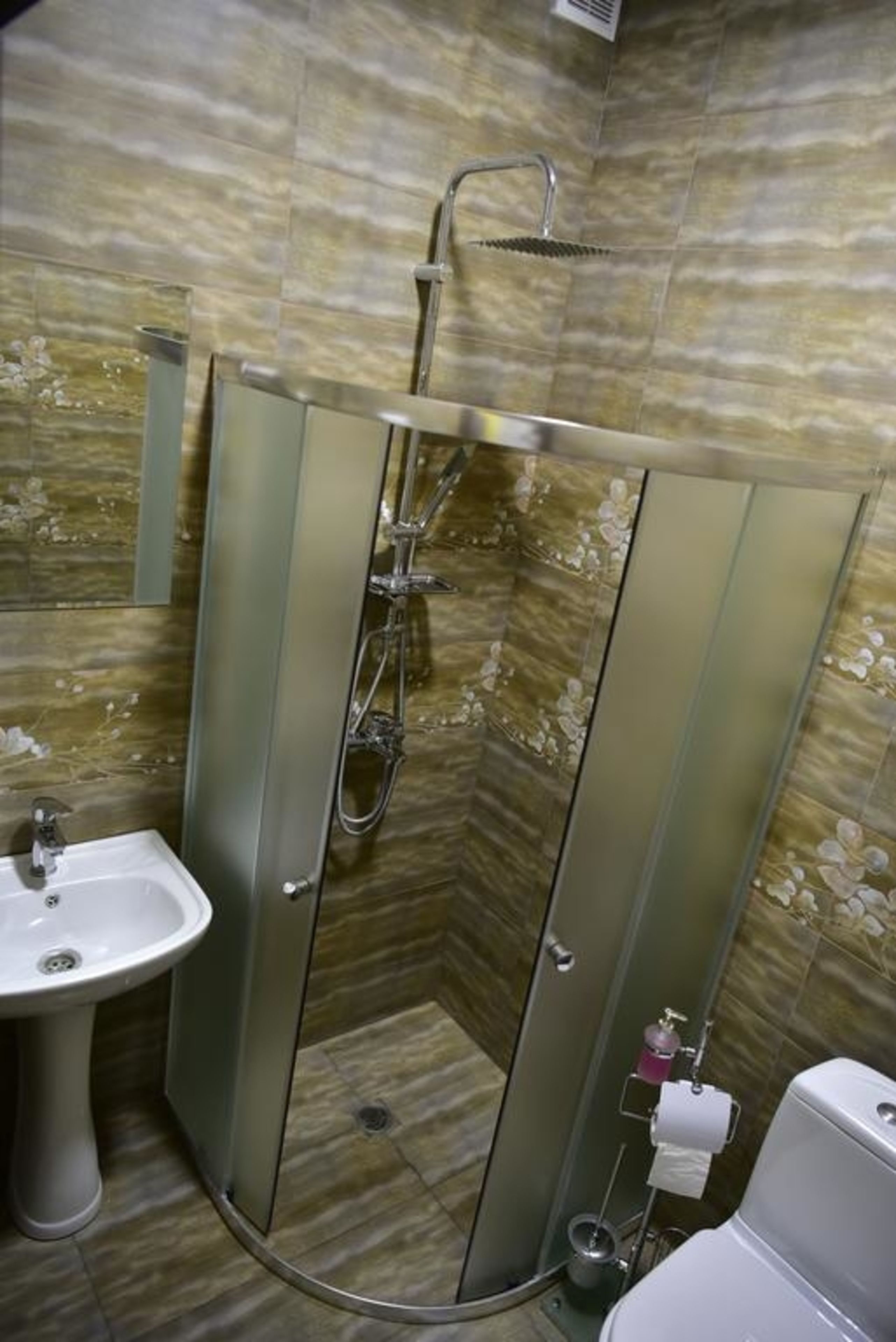 A bathroom with a glass-enclosed shower, a sink, and a toilet.