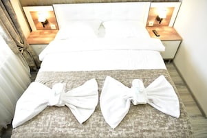 A hotel room with a neatly made bed, two bedside tables with lamps, and a large window with curtains.