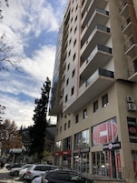 A multi-story hotel with balconies, a visible sign for 'The K Hotel', and a storefront labeled 'ALCORIUM'.