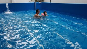 A swimming pool with clear blue water and a blue interior wall.