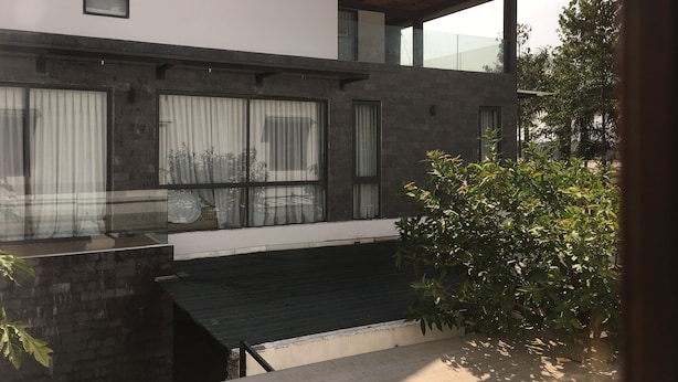 A modern two-story building with large windows, a flat roof, and a balcony.