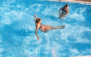 Una piscina con agua cristalina y borde de azulejos.