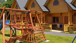 A wooden cabin with a play structure in front. - Domki Agat (Sarbinowo)