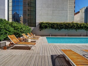 Una piscina al aire libre, sillones reclinables de piscina