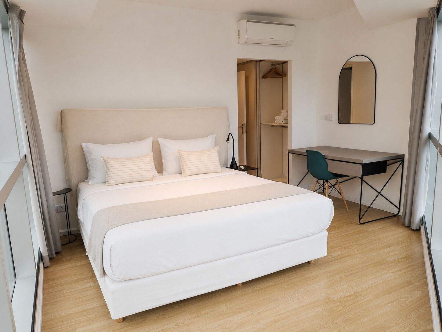 Ein modernes Hotelzimmer mit einem großen Bett, einem Schreibtisch, einem Sessel und einer Klimaanlage.