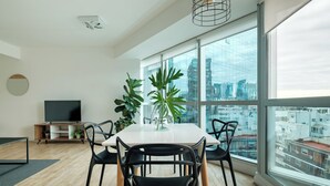 A modern dining area with a large window, a flat-screen TV, and potted plants. - Nido x Bellini Esmeralda (Buenos Aires)