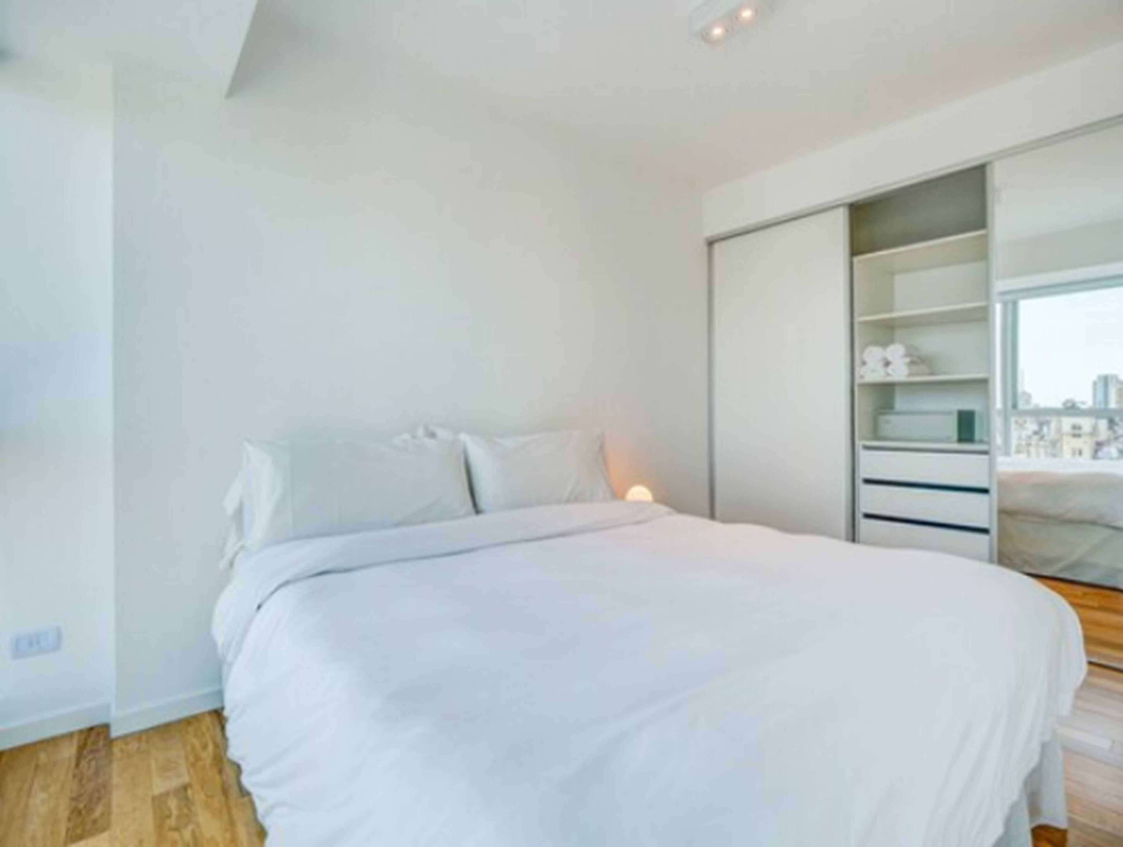 Een moderne slaapkamer met een bed, nachtkastje en een inbouwkast.
